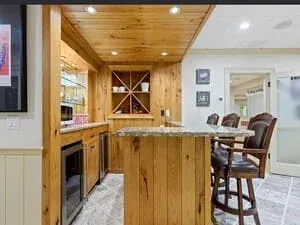 A wine and bar room with a pine plank ceiling, stone counter and a diamond-lattice wine rack.