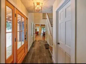 A hallway with wood-framed French doors, a hardwood floor and a lantern pendant overhead.