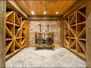 A wine cellar with diamond-bin racking, a brick arch and a stone tiled floor.