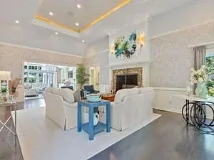 A white living room with a coffered ceiling, a fireplace and pale blue accent furniture.