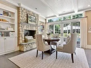 A sitting area with a stone fireplace, flanking built-in shelves and a wall of windows.