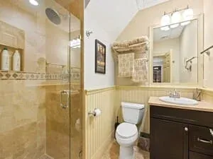 A bathroom with a glass shower enclosure, a dark wood vanity and a framed picture.