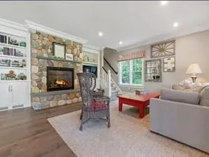 A family room with a stone fireplace, a grey sectional and a small red childrens table.