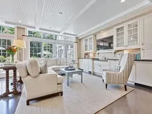 A living room with a wall of windows, a vaulted ceiling and a glass-topped coffee table.