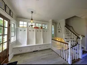 A mudroom with built-in lockers and bench seating at the foot of a white staircase.