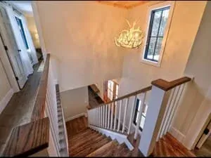 A stairwell with a tall window, a lantern light and a white-painted balustrade.