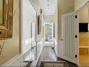 A narrow hallway with a panelled door, a runner and a wall-mounted screen.