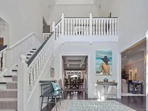 A white staircase turning at a landing, framed pictures on the wall alongside.
