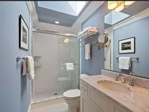 A bathroom with a skylight, a glass shower and a folded towel on a rail.