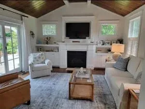 A living room with a fireplace under a sloped white ceiling and a pair of armchairs.